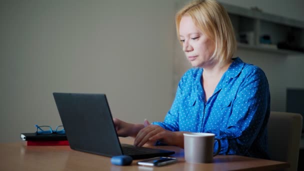 Una mujer rubia feliz terminando su jornada laboral en casa. — Vídeos de Stock