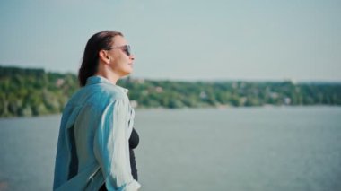 Güzel, genç, yetişkin bir kadın tepenin üstünde dikiliyor ve manzaranın tadını çıkarıyor.