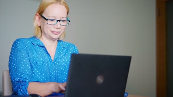 Una mujer rubia feliz terminando su jornada laboral en casa — Vídeos de Stock