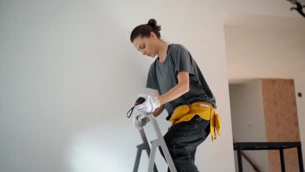 Reparadora profissional com cinto de ferramentas mede a parede com fita métrica — Vídeo de Stock
