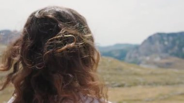 Close-up of a woman with curly hair on a windy day.