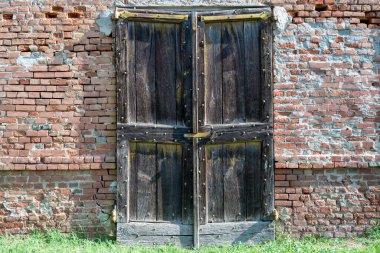 Eski ahşap kapılı eski tuğla ev duvarı.