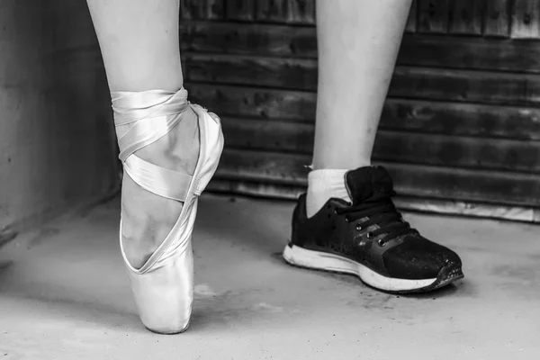 Fötter klädd i dans pointe skor och sportskor. Svartvitt foto — Stockfoto