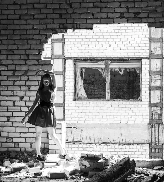 Tunn smal tjej med fräknar på bakgrund av väggen i förstörda byggnaden. Svartvitt foto — Stockfoto