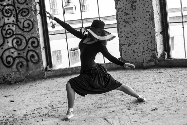 Танцовщица в шляпе и пуантах в красивом темно-сером платье на фоне окна. Классика, современность, современность — стоковое фото