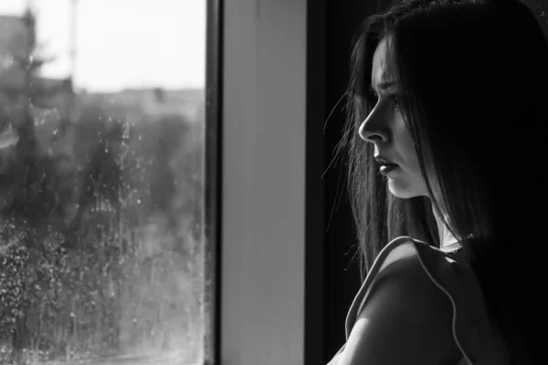 A girl looks out the window. Black and white photo.