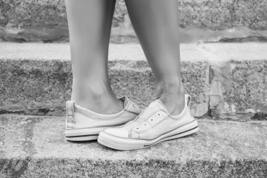 Ayaklar dans pointe ayakkabı, spor ayakkabı taş adımlar arka plan üzerine giymiş. Seksi kadın bacaklar. Siyah ve beyaz fotoğraf