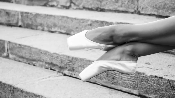 Fötterna klädda i Dans pointe skor, sportskor på bakgrunden av stentrappor. Sexiga kvinnliga ben. Svartvitt foto — Stockfoto