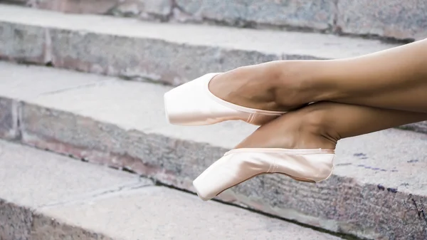 Fötterna klädda i Dans pointe skor, sportskor på bakgrunden av stentrappor. Sexiga kvinnliga ben. — Stockfoto