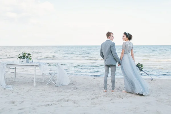 Couple nouvellement marié tenant la main par la mer — Photo