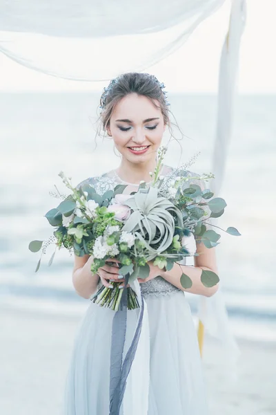 Wunderschöne Braut mit Brautstrauß am Meer — Stockfoto