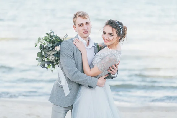 Encantados recién casados abrazándose en la orilla del mar —  Fotos de Stock