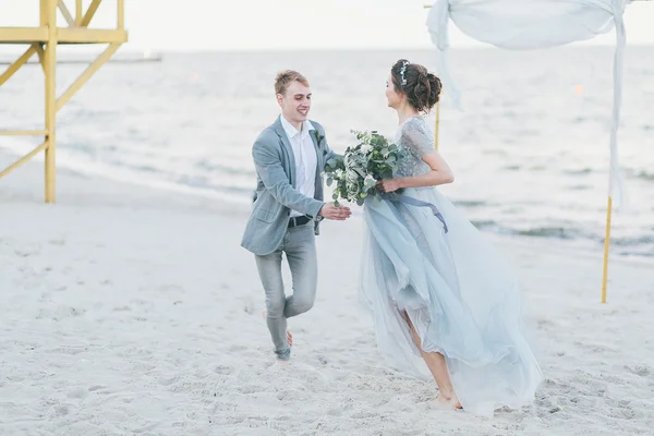 Felizes recém-casados estão se divertindo e correndo pelo mar — Fotografia de Stock