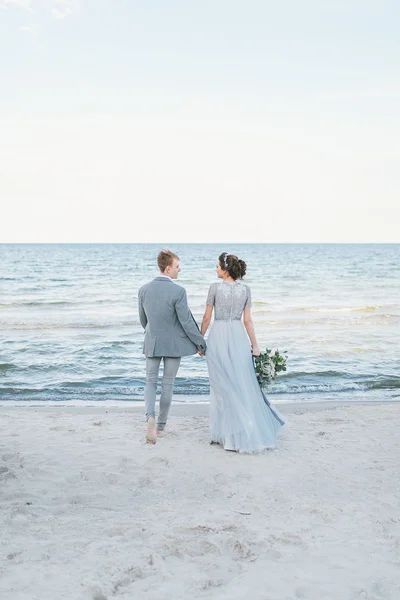 Nouveaux mariés faisant une promenade le long de la plage — Photo