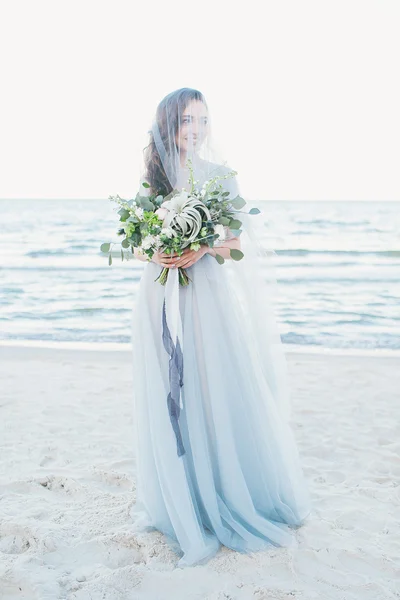 Tenera sposa in velo con bouquet da sposa al mare — Foto Stock