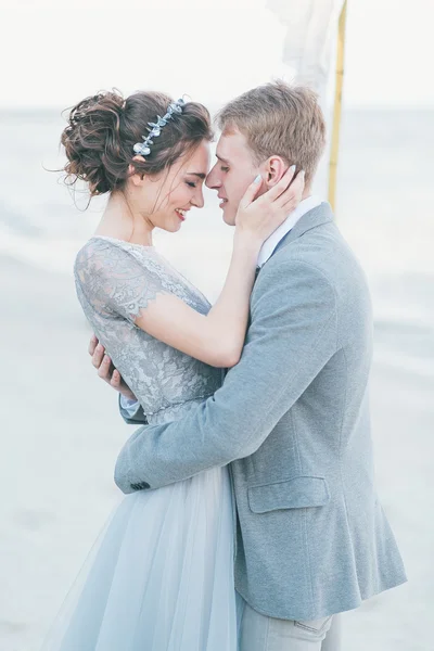 Encantados recién casados abrazándose en la orilla del mar —  Fotos de Stock