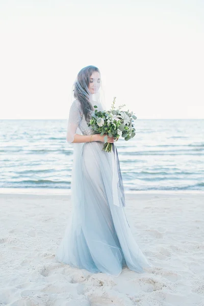 Tenera sposa in velo con bouquet da sposa al mare — Foto Stock