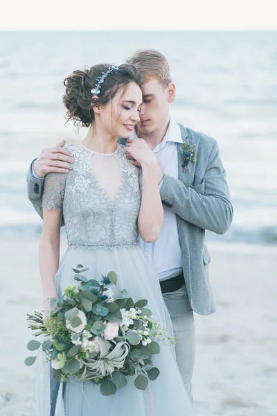 Recién casados abrazándose en la orilla del mar —  Fotos de Stock