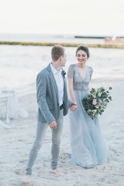 Encantada pareja de recién casados tomados de la mano junto al mar —  Fotos de Stock