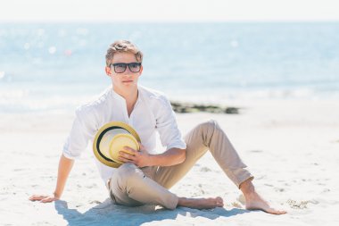 Deniz kıyısı oturan şapkalı iyi görünümlü adam