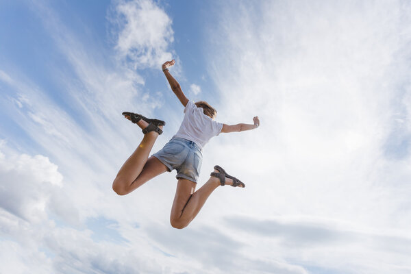 Happy Young Woman Jumping Over Blue Sky 