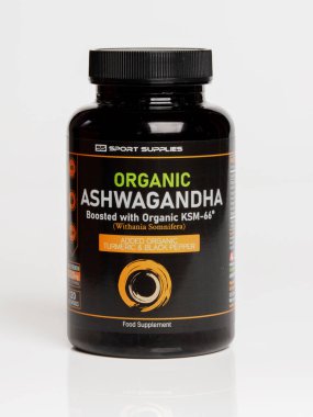 Manchester, İngiltere, 08 Ocak 2026: Beyaz arka plana karşı organik ashwagandha takviyeli siyah şişe.