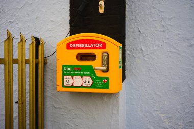 Wallasey, Wirral, İngiltere, 07 Mart 2026: Açık sarı defibrilatör acil durum kullanımı için bir duvarda.