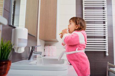 Küçük kız banyoda diş fırçalama.