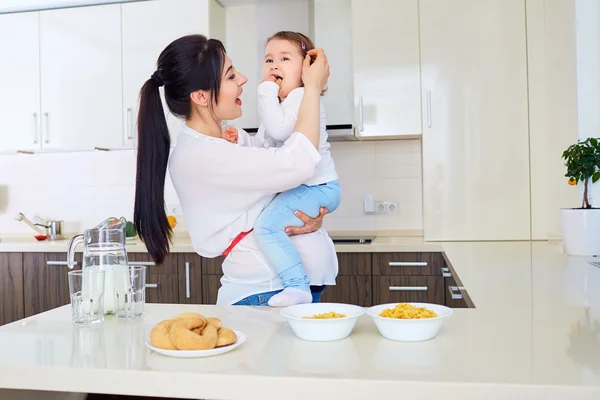 Bonne famille. Mère enceinte et bébé mangeant et souriant dans la cuisine . — Photo