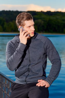 Eğitimden sonra parkta telefonda konuşan sportif adam.