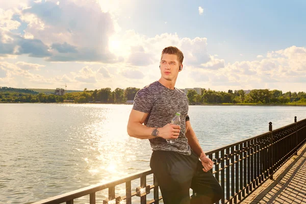 Atleta descansando en un lago en el parque con botella de agua . — Foto de Stock