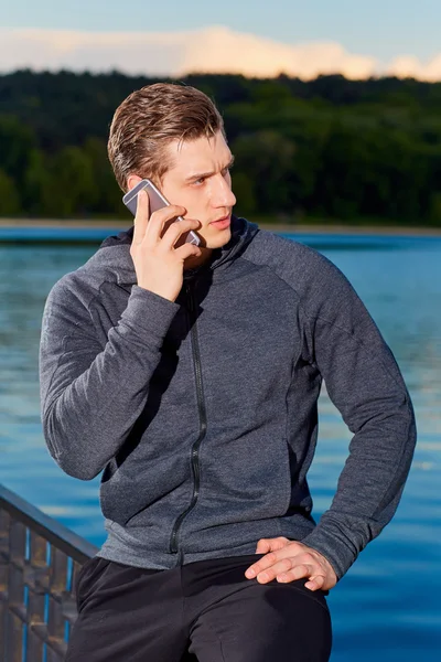 Hombre deportivo hablando por teléfono en el parque después de entrenar . — Foto de Stock