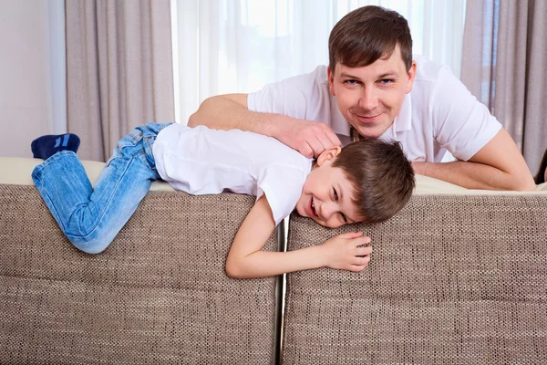 Portrét otce a syna, usmíval se společně na gauči v th — Stock fotografie