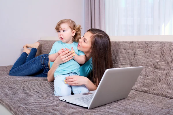 Šťastná rodina žena a dítě s notebookem na pohovce doma. — Stock fotografie