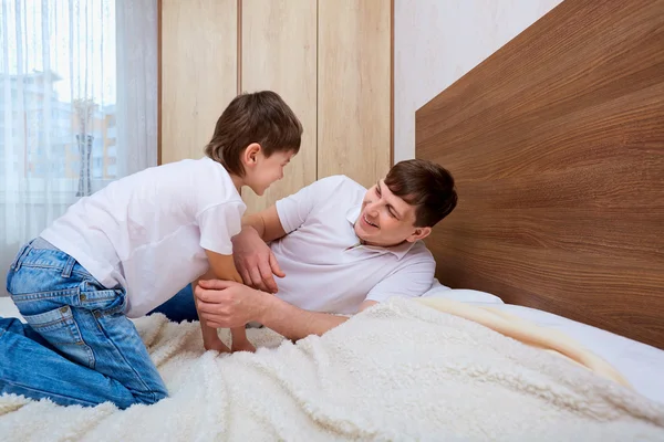 快乐的父亲和儿子在床上笑着说. — 图库照片
