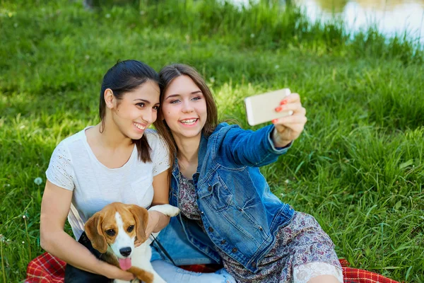 Meninas jovens tirando fotos de si mesma e seu cão ao ar livre in natu — Fotografia de Stock