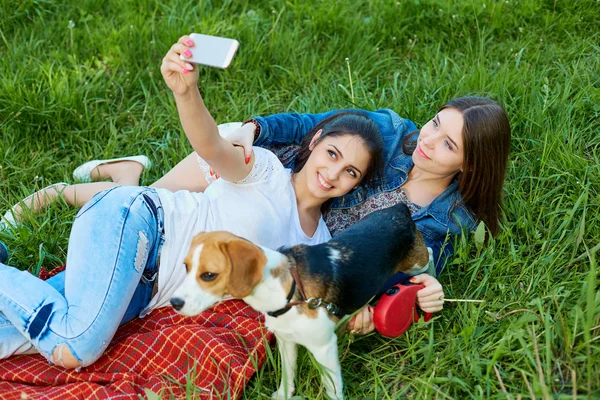 Duas meninas adoráveis posando com seu cão no parque . — Fotografia de Stock