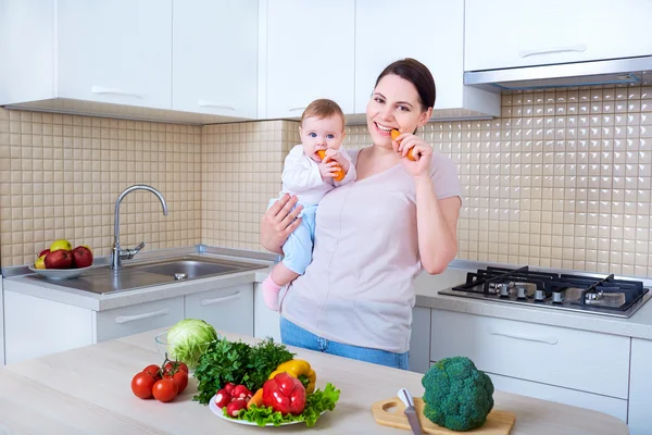 Mère et bébé mangeant des carottes dans la cuisine — Photo