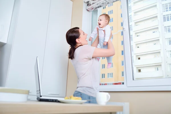 Mama gra z dzieckiem w oknie w białych kuchni — Zdjęcie stockowe