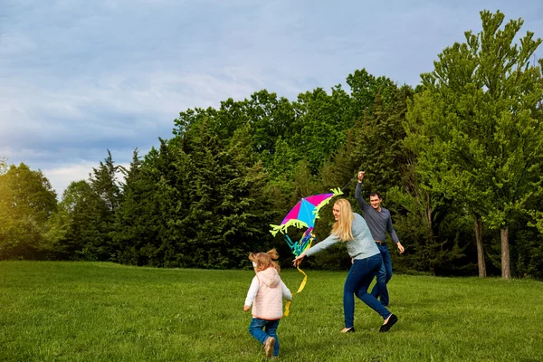 Мама, тато і дитина літають на повітряному змії. Щаслива сім'я грає, посміхається — стокове фото