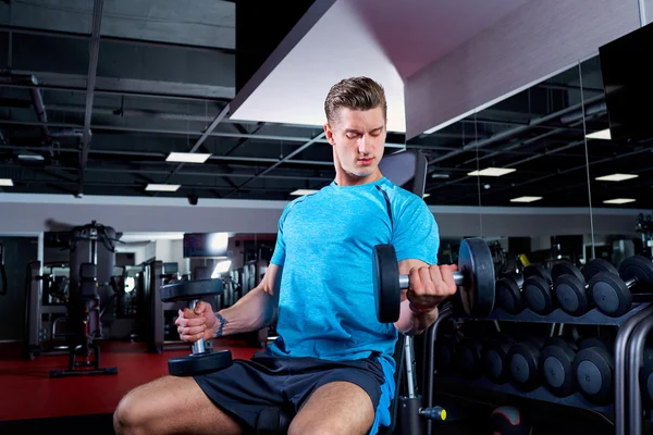 Kaslı adam spor salonunda dumbbells ile çalışma dışarı. — Stok fotoğraf