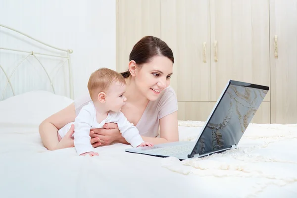 Maman et bébé regardant un ordinateur portable et souriant heureux . — Photo