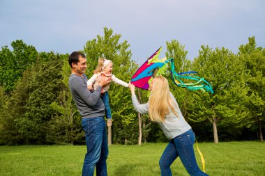 Doğada mutlu bir aile. Baba, anne ve kızı çocuk bir kit uçan