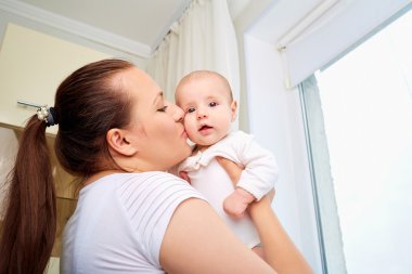 Sevgi dolu bir anne bebeği ile bir pencere üzerinde oynama.