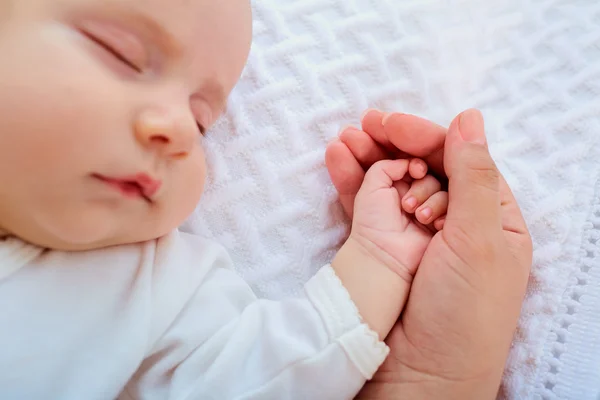 Fechar a mão de um bebê na mão da mãe . — Fotografia de Stock