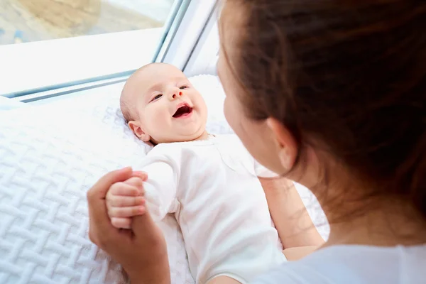 Happy family.Mother playing with newborn baby near the window. — Stock Photo, Image