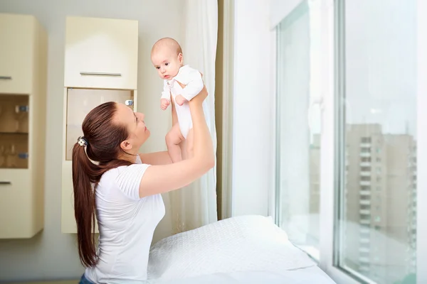 Mother throws up baby, playing at home. — Stock Photo, Image