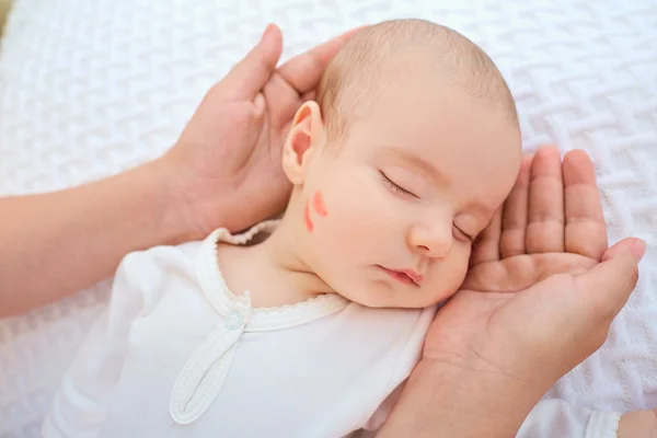 Cabeça de bebê recém-nascido nas mãos dos pais.Beijo na bochecha do bebê — Fotografia de Stock
