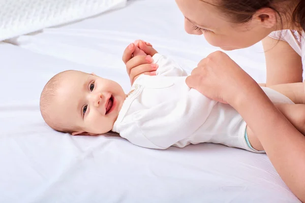 Feliz madre sonriente con el bebé en el mal . — Foto de Stock