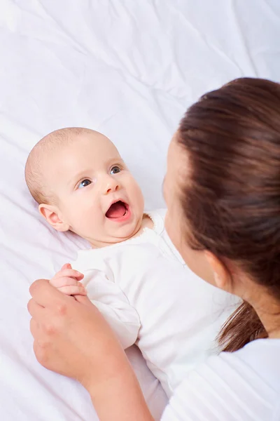 Madre y bebé en la cama. Hermoso sonriente lindo bebé — Foto de Stock